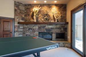 Rec room featuring plenty of natural light and a stone fireplace