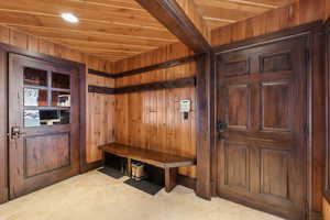 Mudroom with light tile patterned floors, wooden ceiling, and wood walls