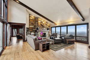 Living room with light wood-type flooring, a fireplace, beamed ceiling, and a water view