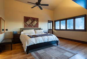 Bedroom with ceiling fan, high vaulted ceiling, and hardwood / wood-style flooring