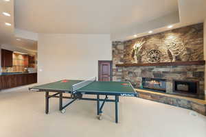 Rec room with light colored carpet and a fireplace