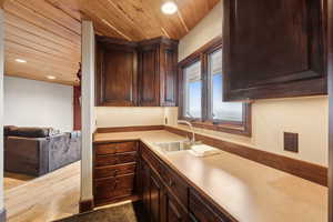Kitchen featuring dark brown cabinetry, sink, wood ceiling, and light hardwood / wood-style flooring