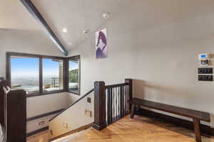 Stairway featuring wood-type flooring, vaulted ceiling, and a textured ceiling