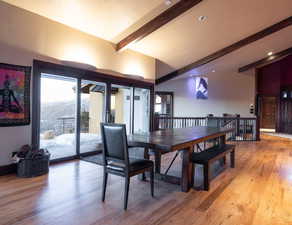 Dining area with a mountain view, light hardwood / wood-style flooring, and lofted ceiling with beams