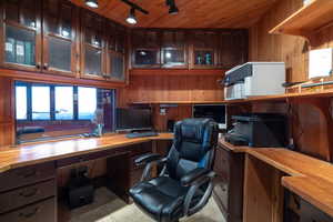 Office space with built in desk, light tile patterned flooring, wood ceiling, and wooden walls