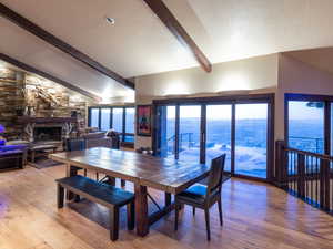 Dining room with a fireplace, a water view, and vaulted ceiling with beams