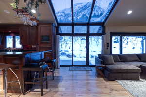 Living room with a mountain view, sink, expansive windows, a high ceiling, and light hardwood / wood-style flooring