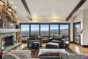 Living room featuring vaulted ceiling with beams, light hardwood / wood-style flooring, a textured ceiling, a mountain view, and a fireplace