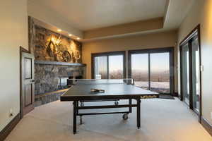 Playroom featuring light colored carpet, a textured ceiling, and a stone fireplace