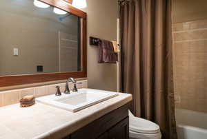 Full bathroom with shower / bath combo with shower curtain, toilet, and vanity