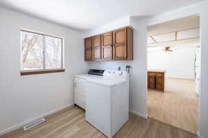 Laundry room featuring light wood-type flooring, ceiling fan, washer and clothes dryer, and cabinets