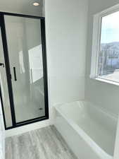 Bathroom with hardwood / wood-style flooring, plus walk in shower, and a wealth of natural light