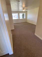 Carpeted spare room with ceiling fan and a textured ceiling