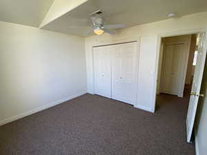 Second bedroom featuring a closet, ceiling fan, and dark carpet