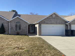 Ranch-style house featuring a garage and a front lawn