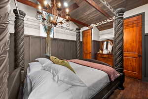 Bedroom featuring dark wood-type flooring, wooden ceiling, lofted ceiling with beams, and a wall mounted air conditioner