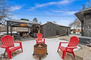 Snow covered patio with central AC, a gazebo, an outdoor fire pit, and a storage shed