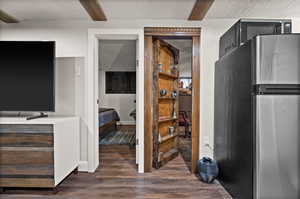 Kitchen featuring dark hardwood / wood-style floors, beamed ceiling, and stainless steel refrigerator