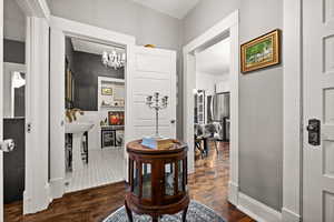 Hall featuring dark hardwood / wood-style floors and an inviting chandelier