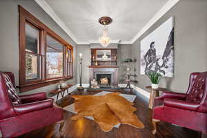 Living room featuring dark hardwood / wood-style floors, crown molding, and a chandelier