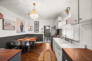 Kitchen featuring wood counters, white cabinetry, pendant lighting, and a healthy amount of sunlight