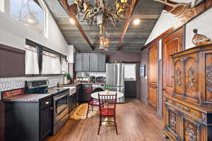 Kitchen featuring appliances with stainless steel finishes, washer / dryer, decorative backsplash, a chandelier, and wooden ceiling