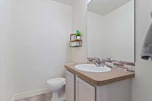 Bathroom featuring vanity, toilet, tile patterned floors, and decorative backsplash