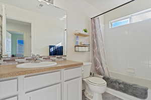 Full bathroom featuring vanity, backsplash, shower / tub combo, and toilet