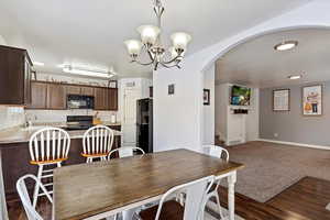 Dining space with dark wood-type flooring, sink, and an inviting chandelier