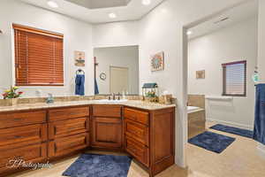 Bathroom featuring a relaxing tiled tub, vanity, and tile patterned flooring