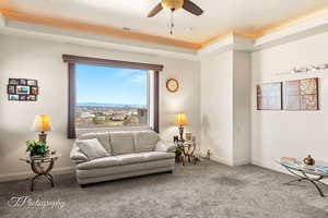 Carpeted living room with a mountain view, a raised ceiling, and ceiling fan