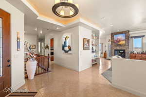 Entryway featuring a fireplace, light tile patterned floors, and a raised ceiling