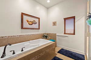 Bathroom with a relaxing tiled tub and tile patterned flooring