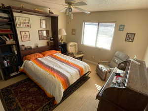 Carpeted bedroom featuring a textured ceiling and ceiling fan