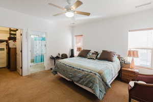 Bedroom featuring light colored carpet, ensuite bathroom, and ceiling fan