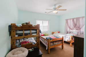 Carpeted bedroom featuring ceiling fan