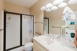 Bathroom featuring toilet, a shower with door, and vanity