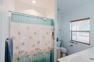 Bathroom with curtained shower, toilet, and vanity