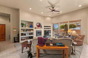 Tiled living room featuring built in shelves and ceiling fan