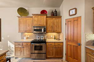 Kitchen featuring appliances with stainless steel finishes, tasteful backsplash, and light tile patterned flooring