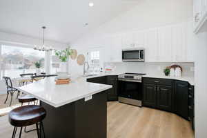 Kitchen featuring sink, tasteful backsplash, white cabinetry, and appliances with stainless steel finishes