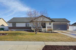 Single story home featuring a garage, covered porch, and a front yard