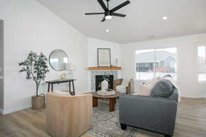 Living room featuring vaulted ceiling, ceiling fan, a tile fireplace, and wood-type flooring