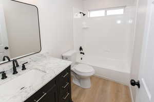 Full bathroom with toilet, hardwood / wood-style flooring, washtub / shower combination, and vanity