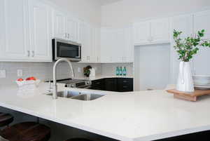 Kitchen featuring decorative backsplash, sink, white cabinetry, and stainless steel appliances