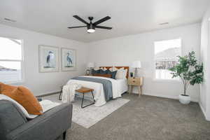 Carpeted bedroom featuring ceiling fan and multiple windows