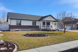 Ranch-style house featuring covered porch, a front lawn, and a garage