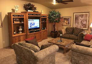 Living room featuring ceiling fan, light carpet, and vaulted ceiling