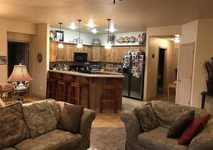 Kitchen featuring a kitchen bar, hanging light fixtures, stove, kitchen peninsula, and stainless steel fridge