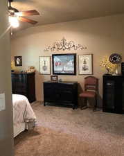 Carpeted bedroom with ceiling fan and lofted ceiling